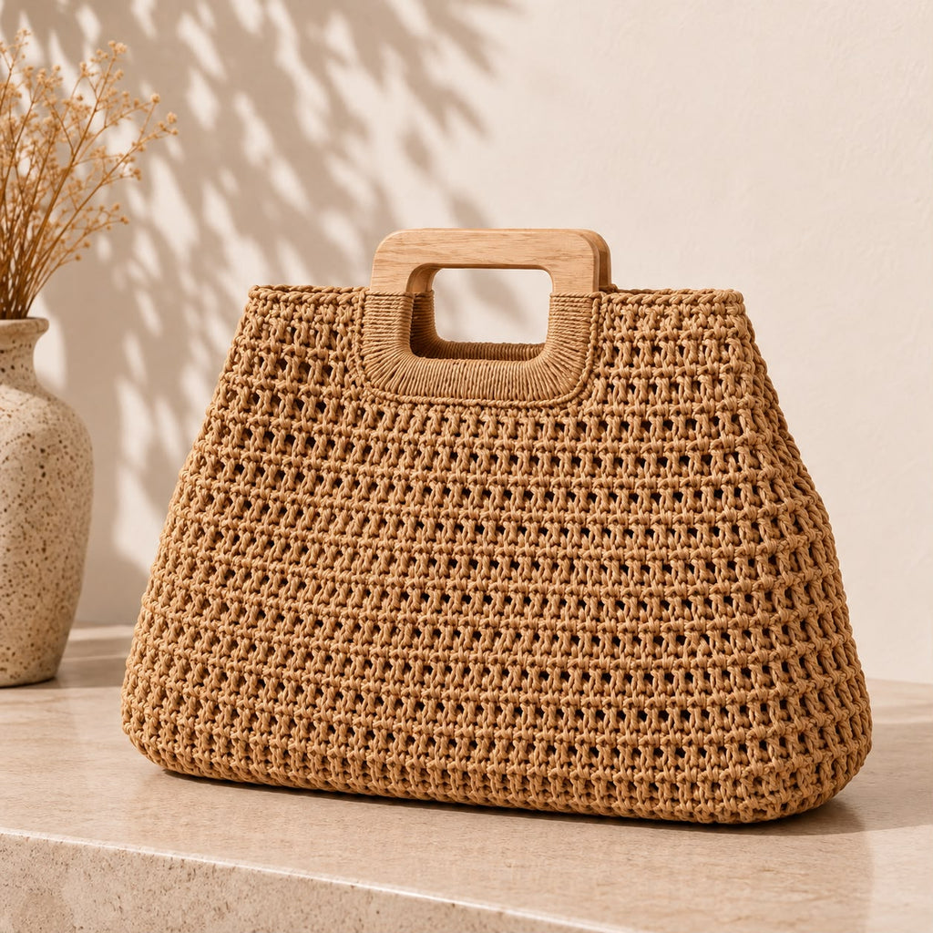 Bolso tejido en fibra natural con asa de madera junto a un jarrón